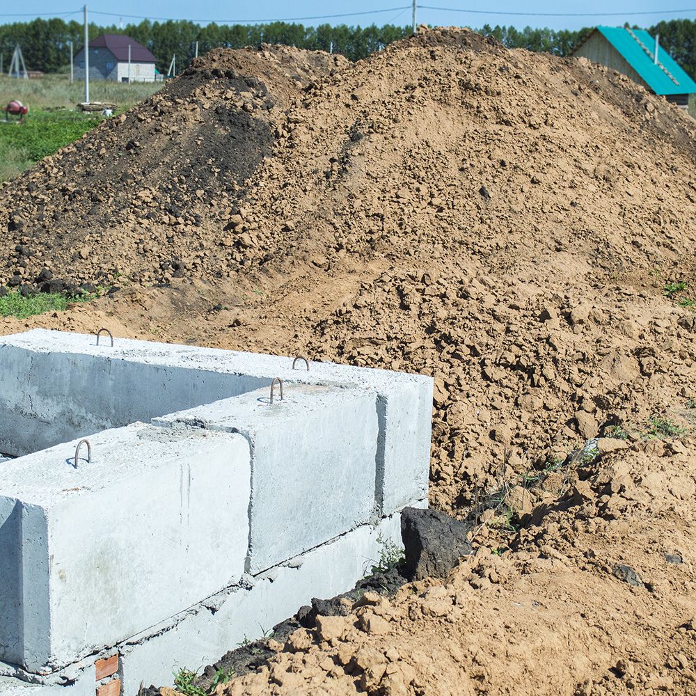 Ein Sandhaufen und eine graue Steinmauer