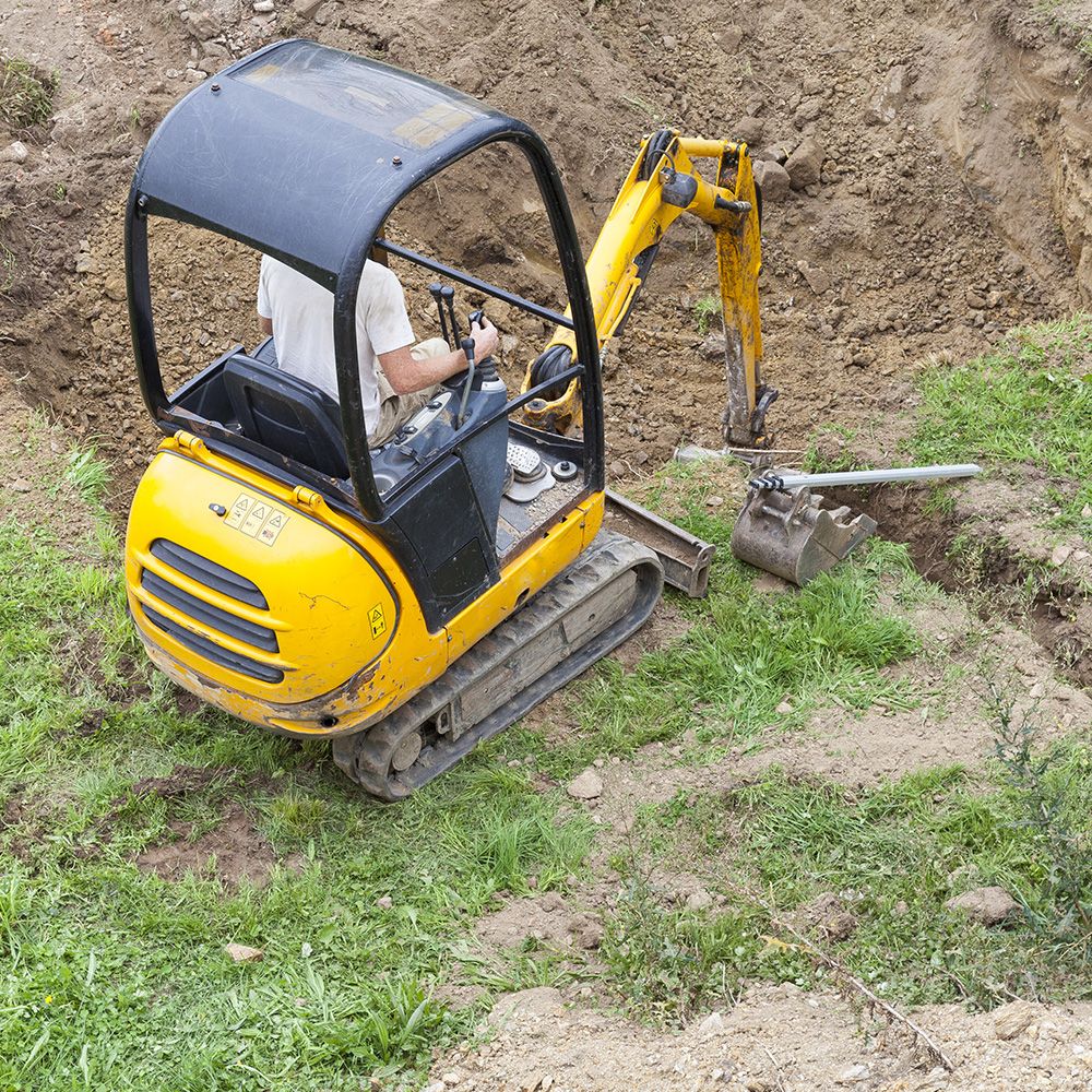 Eine Person in einem gelben Bagger hebt ein Loch aus