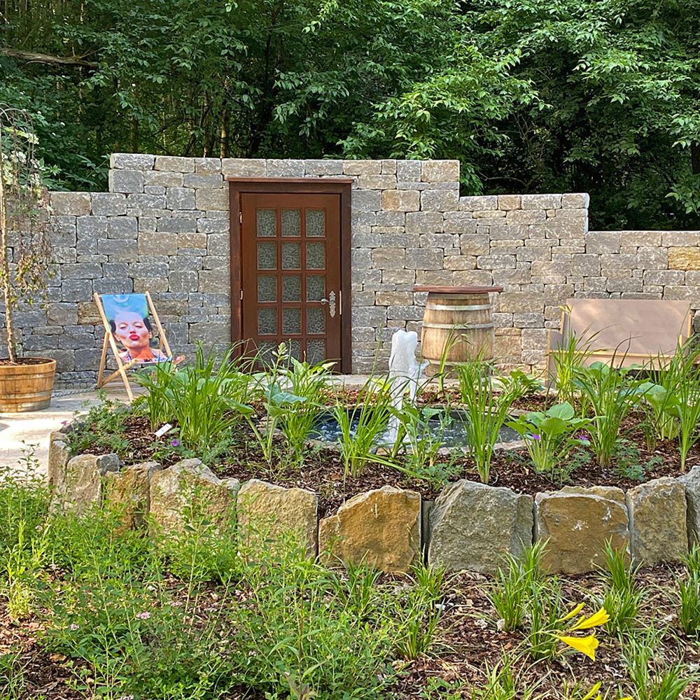 Ein bepflanzter Rundgarten mit einer Steinmauer im Hintergrund